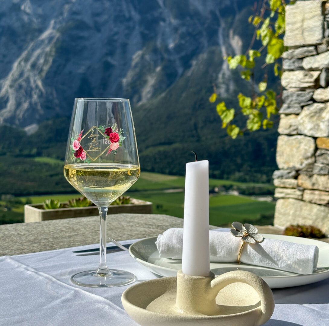 Ein dekorierter Hochzeitstisch mit personalisierten Weingläsern, einer Kerze und einem Teller.
